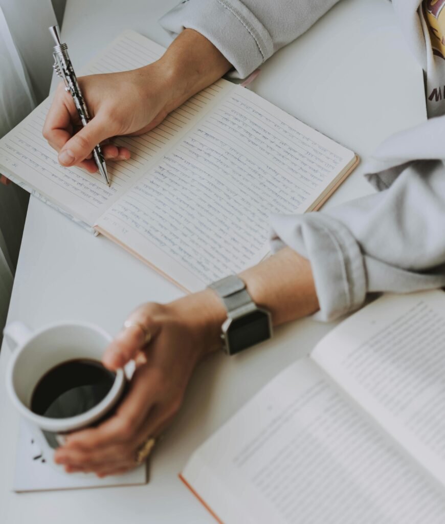 Mujer escribiendo en libro con taza de café